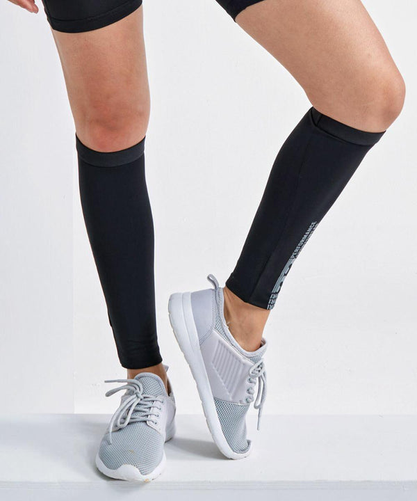Person wearing gray Tri-Dri TR093 athletic shoes, black knee-high socks, and black shorts, with legs crossed.