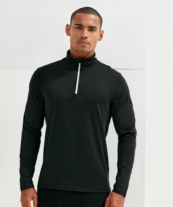 A man stands wearing a black, long-sleeve, zip-up top, looking directly at the camera. The background is plain and white. He is dressed in the Tri-Dri TR111.