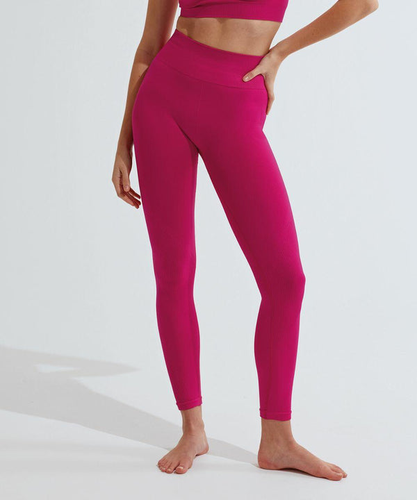 Person in bright pink athletic wear, including a TriDri TR215 sports bra and high-waisted leggings, posing on one leg in a studio with a white background. Face is not visible.