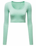 The TR224 crop top by Tri-Dri features a ribbed design with long sleeves and a scoop neckline, showcased in light green against a white background. The size label XS is clearly visible inside the neckline.