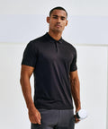 A person wearing a black polo shirt and holding a Tri-Dri TR505 stands against a plain background, looking at the camera.