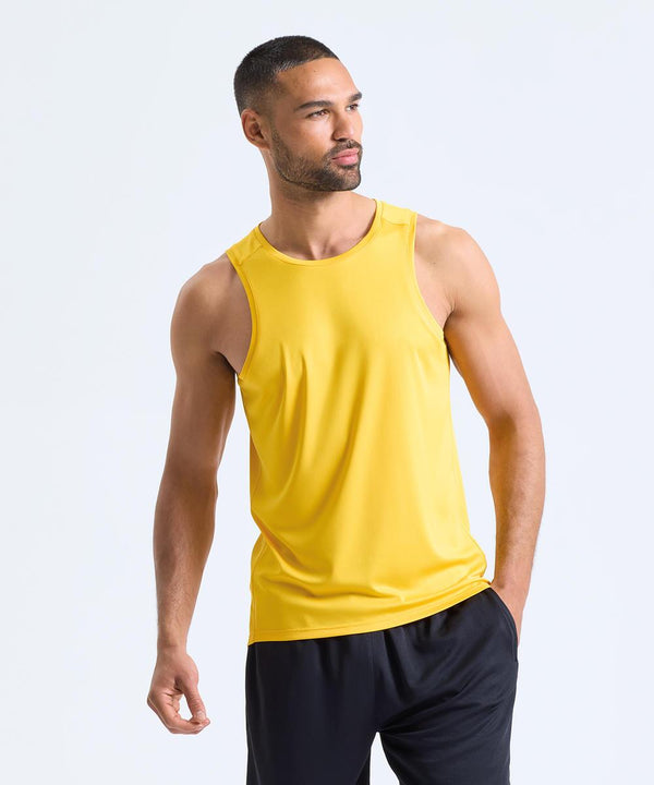 A man wearing the TriDri Ion-Charge performance vest stands against a plain, light background, looking to the side with one hand in his pocket.