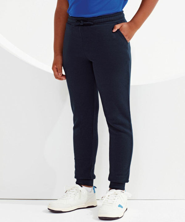 A person wearing a blue shirt, navy blue jogger pants, and white Tri-Dri TR55B sneakers stands with one hand in a pocket against a white background.