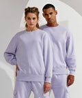 Two individuals stand side by side, both wearing matching light purple TR603 sweatshirts and pants from TriDri, with a plain background behind them.