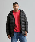 A person stands facing forwards, wearing the 2786 Solitude recycled hooded jacket over a red sweatshirt and blue jeans, against a plain light grey background.