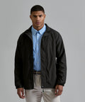 A man stands facing forwards against a plain grey background, wearing a light blue button-down shirt, beige trousers, and the 2786 Recycled super-lightweight jacket in black.