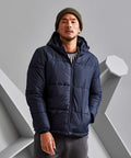 A person in a green beanie and navy blue 2786 TS027 stands against a gray geometric background.