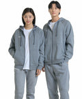 Two people wearing matching gray Under Armour UA041 hoodies and sweatpants stand side by side, smiling at the camera. Both UA041 hoodies have zippers and drawstrings, and they are each wearing white shirts underneath.