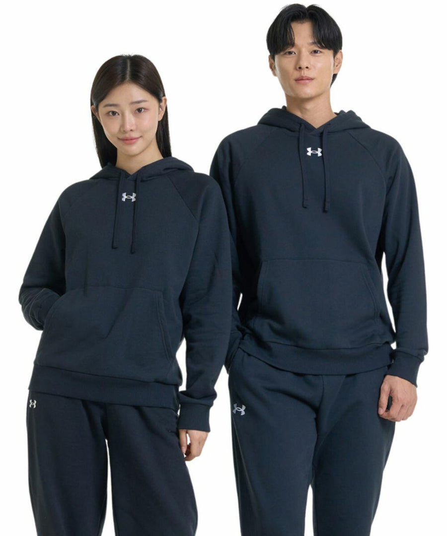 A woman and a man are standing side by side, both wearing matching black UA048 hoodies and pants with a small Under Armour logo.