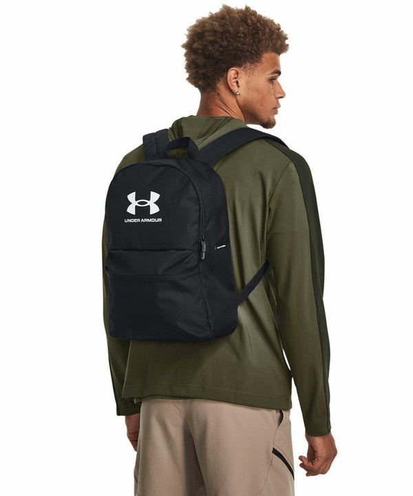 Man wearing a green hoodie and khaki pants with a black Under Armour UA056 backpack featuring a white logo.