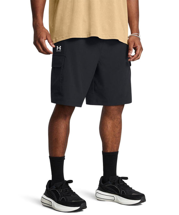 A person wearing a beige T-shirt, Under Armour UA Vibe cargo shorts in black, black crew socks, and black and white trainers stands against a plain white background.