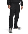 A person wearing Under Armour UA Rival woven windbreaker trousers stands against a plain white background, with only their lower half visible.