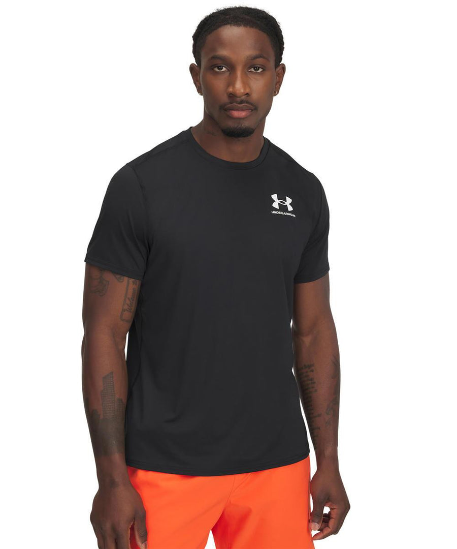 A man faces forwards wearing a black Under Armour HeatGear fitted t-shirt featuring a white logo on the chest and bright orange shorts. The background is plain white.
