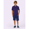 A boy wearing a UC103 Purple Uneek childrens pique polo shirt with Blue shorts