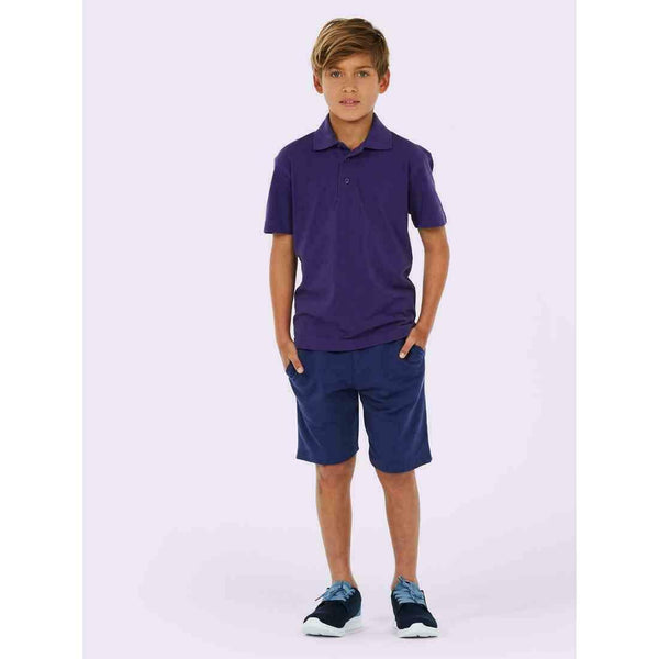 A boy wearing a UC103 Purple Uneek childrens pique polo shirt with Blue shorts