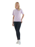 A woman wearing a UC106 Lilac Uneek ladies polo shirt with Black trousers