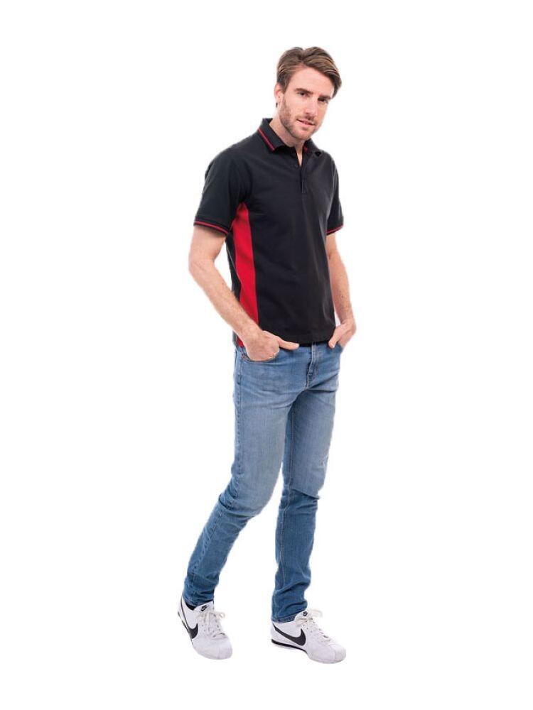 A man wearing a UC117 Black and Red Uneek two tone polo shirt with blue jeans and white trainers