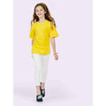 A girl wearing a UC306 Yellow Uneek childrens t-shirt with White jeans
