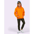 A boy wearing a UC503 Orange Uneek childrens hooded sweatshirt with Camoflauge joggers