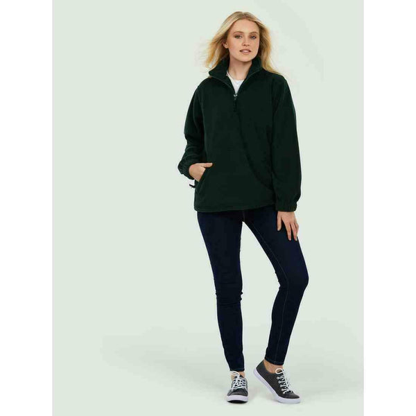 A woman wearing a UC602 Bottle Green Uneek adults classic 1/4 zip fleece with Blue jeans