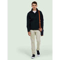 A man wearing a UC611 Black Uneek deluxe soft shell jacket with Beige trousers