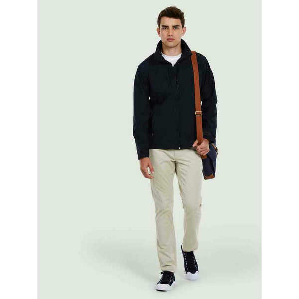 A man wearing a UC611 Black Uneek deluxe soft shell jacket with Beige trousers
