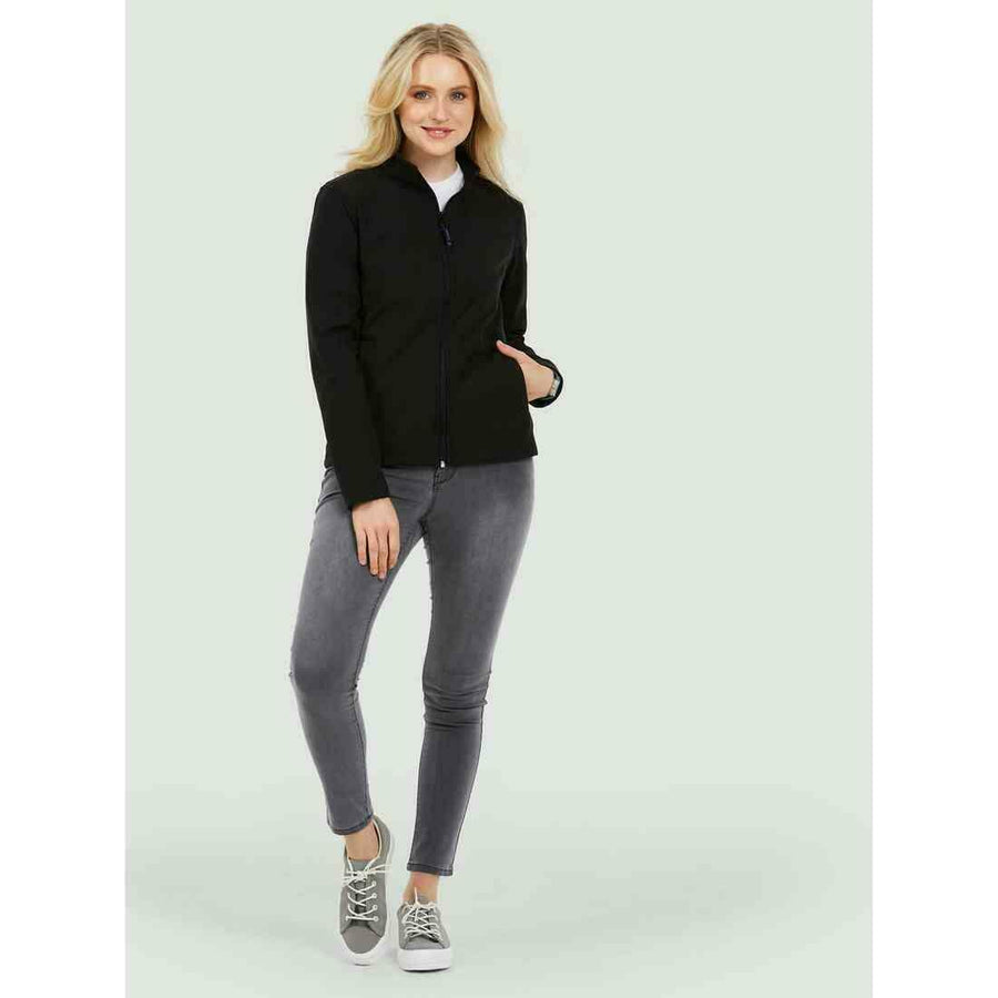 A woman wearing a UC613 Black Uneek ladies classic soft shell jacket with Grey jeans