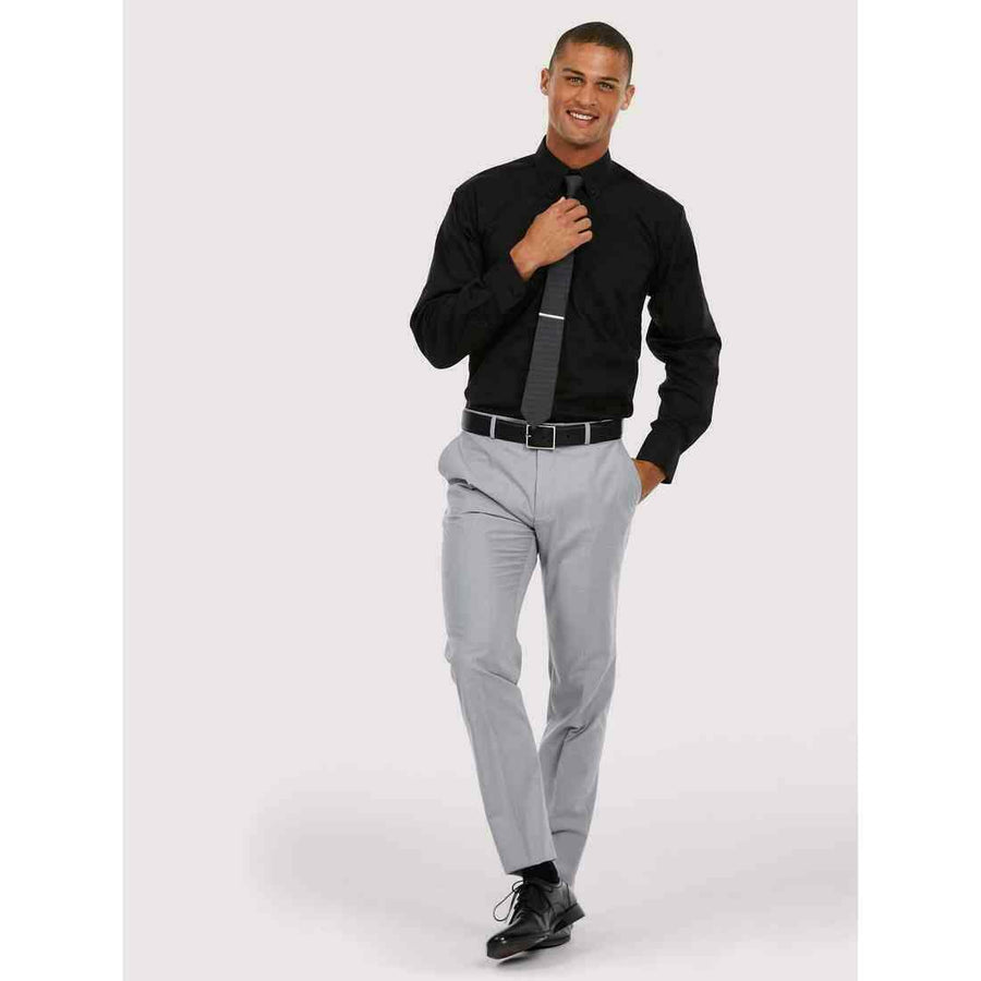 A man wearing a UC701 Black Uneek pinpoint oxford L/S shirt with Grey trousers