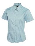 A light blue short-sleeved Uneek UC704 button-up shirt displayed on a white background.