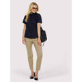 A woman wearing a UC704 Black Uneek ladies pinpoint oxford Short sleeved shirt with beige trousers