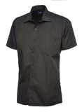 A black, short-sleeved UC710 dress shirt with a button-up front and a single chest pocket, displayed on a plain background by Uneek.