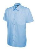 A light blue, short-sleeved UC710 dress shirt with a button-up front and a single chest pocket, displayed on a plain background by Uneek.