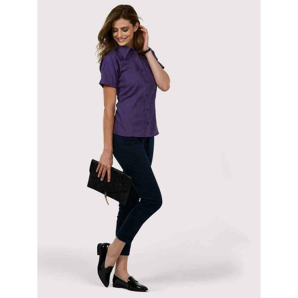 A woman wearing a UC712 Purple Uneek ladies poplin Short sleeved shirt with Navy trousers