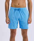 A person wearing Wombat Men's Terry shorts in light blue stands against a plain light background. The photo captures them from mid-torso to just above the knees.