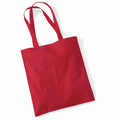 A bright red tote bag from Westford Mill, model WM101, with two handles lies flat against a plain white background. The fabric appears smooth and the bag features a simple design, making it suitable for everyday use or carrying items.