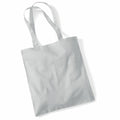 A Westford Mill WM101 tote bag, crafted from light gray canvas with two handles, is resting on a white background. The soft and slightly crumpled fabric suggests a casual and reusable design.