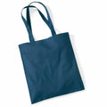 A blue Westford Mill tote bag, known as WM101, featuring two long handles, is lying on a white surface. The bag is flat and boasts a simple, plain design.