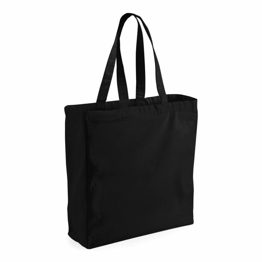 A Westford Mill WM108 plain black tote bag with two handles is standing upright against a white background.