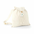 A beige WM185 canvas drawstring backpack from Westford Mill, featuring a button closure and a tag attached to the strap.