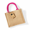 Introducing the WM412 by Westford Mill: A tan jute tote bag featuring vibrant pink handles. This eco-friendly design has a small brown tag labeled "jute," making it perfect for casual use.