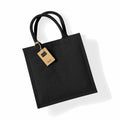 A black jute tote bag known as the Westford Mill WM413, featuring two handles and a brown tag attached.