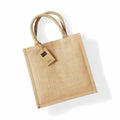 The WM413 from Westford Mill is a beige jute tote bag featuring two woven handles and an attached tag.