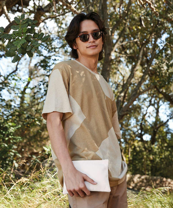 A person wearing sunglasses and a patterned beige t-shirt stands outdoors, holding a Westford Mill WM530. Trees and greenery are in the background.
