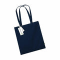 A WM801 tote bag by Westford Mill, featuring a navy blue color with two long handles, showcased against a white background. A tag with text is attached to one handle.