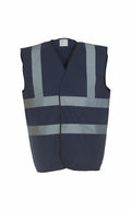 The Yoko YK001 safety vest, featuring a dark blue color with reflective gray horizontal and vertical stripes, is showcased against a white background. It has a sleeveless design with a V-neck style.
