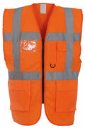 The Yoko YK002 is a high-visibility safety vest in bright orange, featuring silver reflective stripes on the front and sides. It is equipped with multiple pockets and a clear plastic ID holder on the chest for enhanced functionality in work environments.