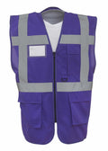 The Yoko YK002 is a purple and gray reflective safety vest designed with multiple pockets and a zippered front. It includes horizontal and vertical reflective stripes for enhanced visibility and features a clear ID pocket on the upper left side.