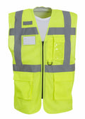 The Yoko YK015 is a bright yellow safety vest featuring gray reflective strips across the chest and shoulders. It includes pockets and a clear ID holder on the chest for enhanced visibility and safety.