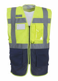 Introducing the Yoko YK015, a high-visibility safety vest featuring a bright yellow mesh design with gray reflective stripes. It boasts multiple pockets, a convenient zipper closure, and a navy blue lower portion.