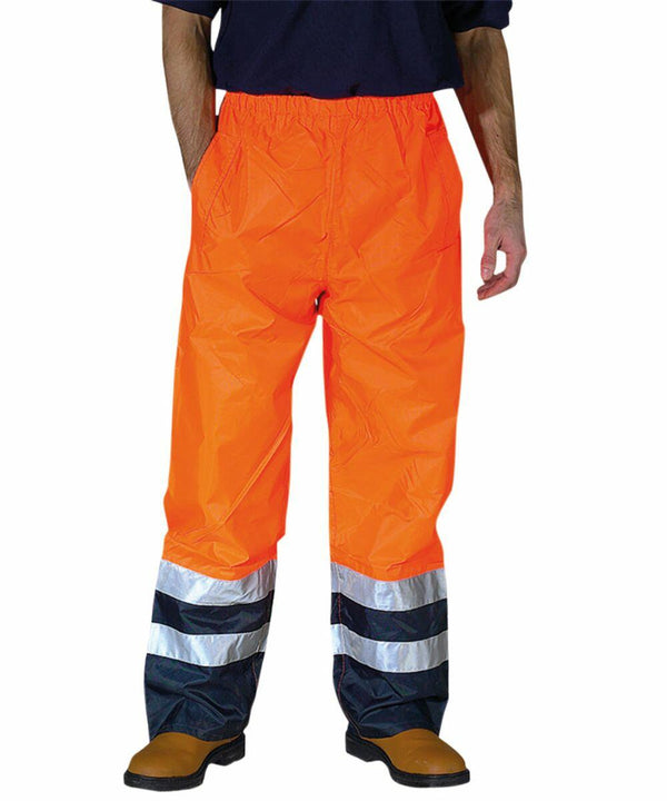 Person wearing Yoko YK072 high-visibility pants with reflective stripes near the bottom, paired with a dark shirt and brown work boots.